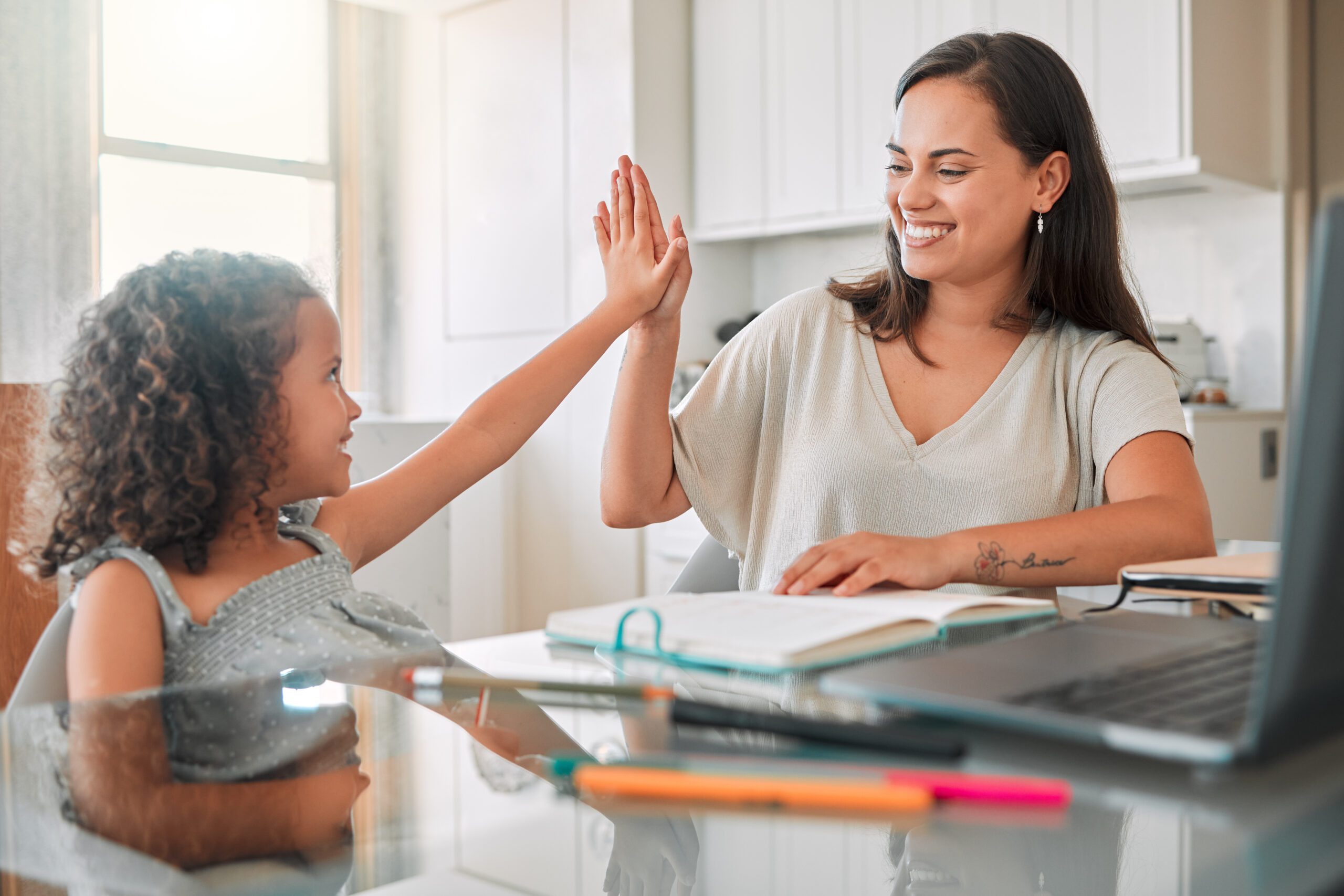 Girl and woman high-fiving in a bright kitchen