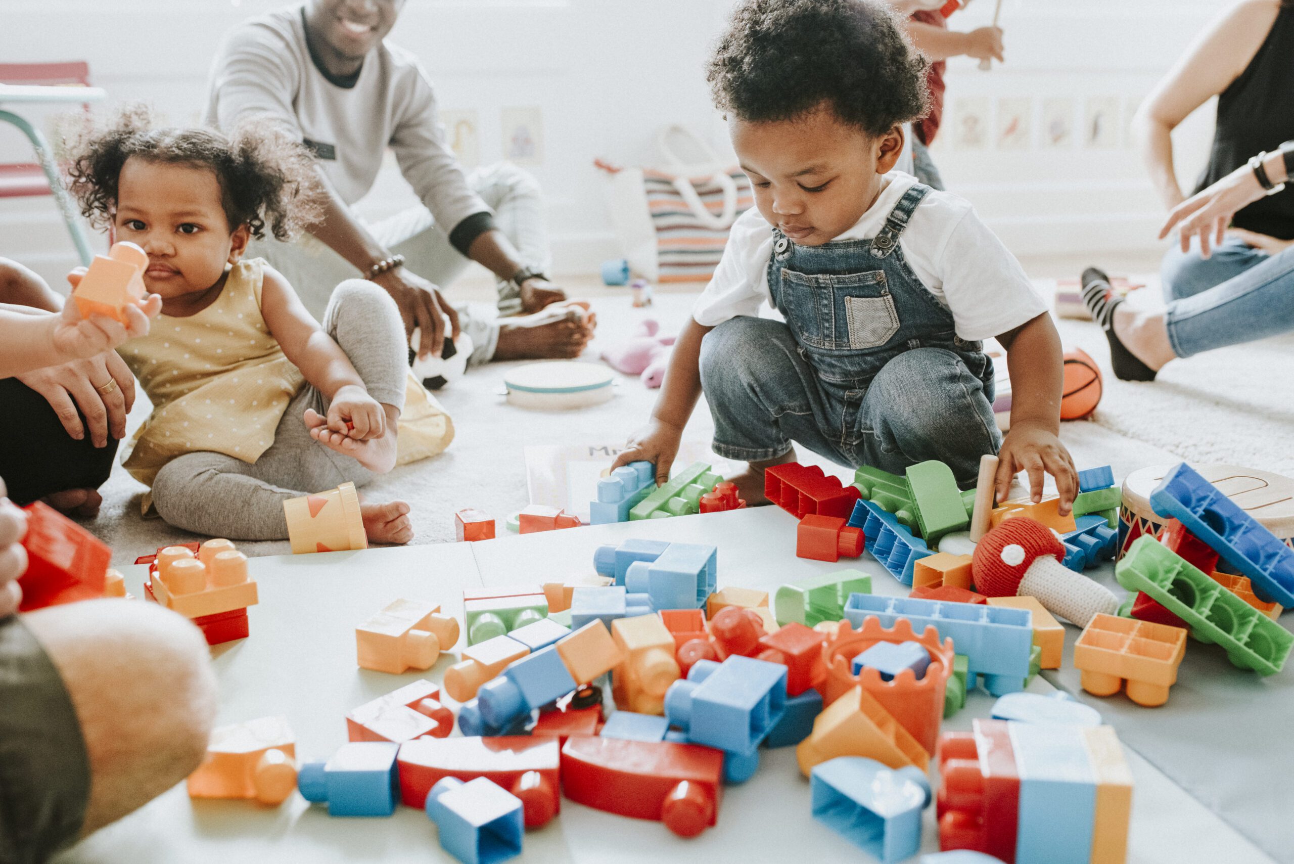 Children and an adult playing with colorful building blocks