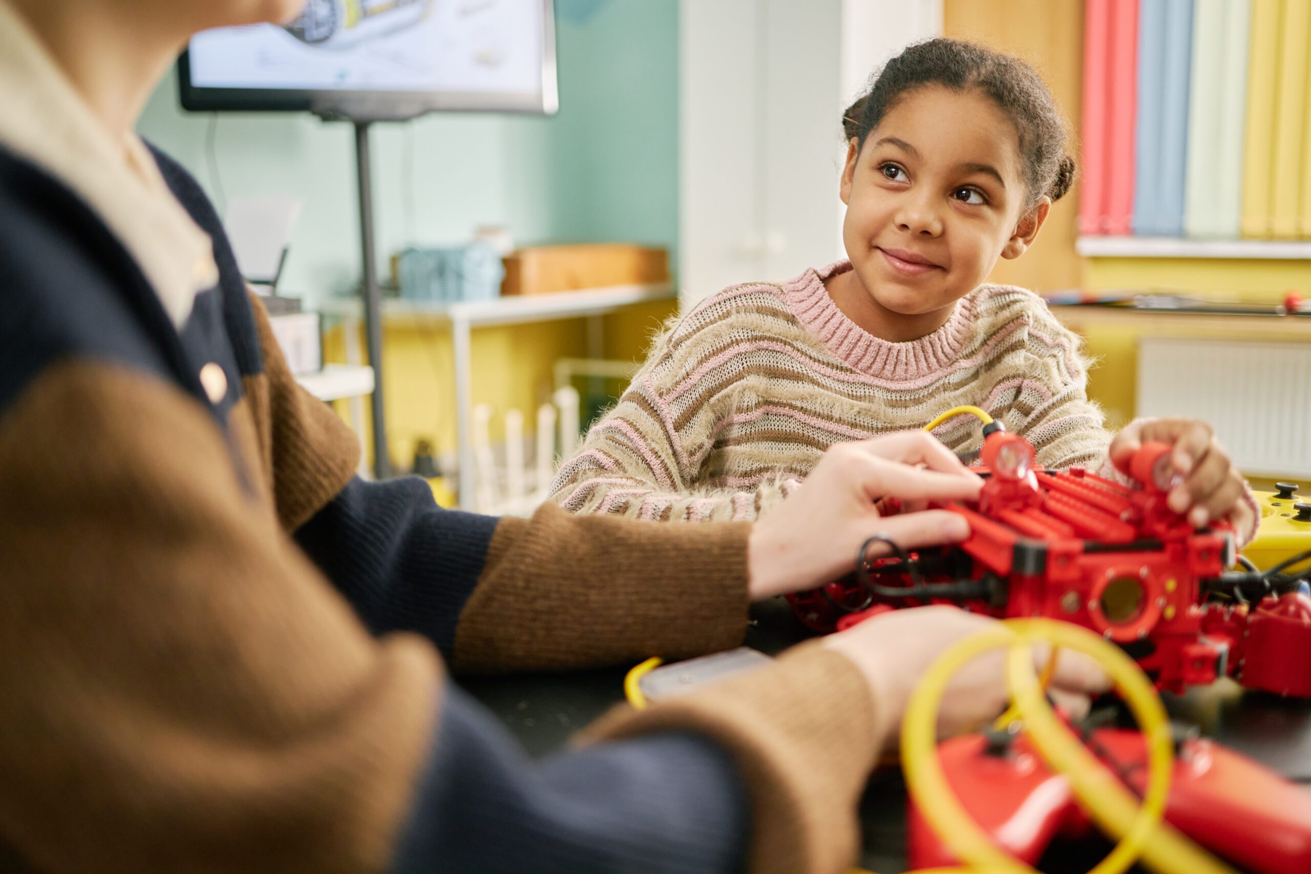 Girl building a robot with adult support in a classroom