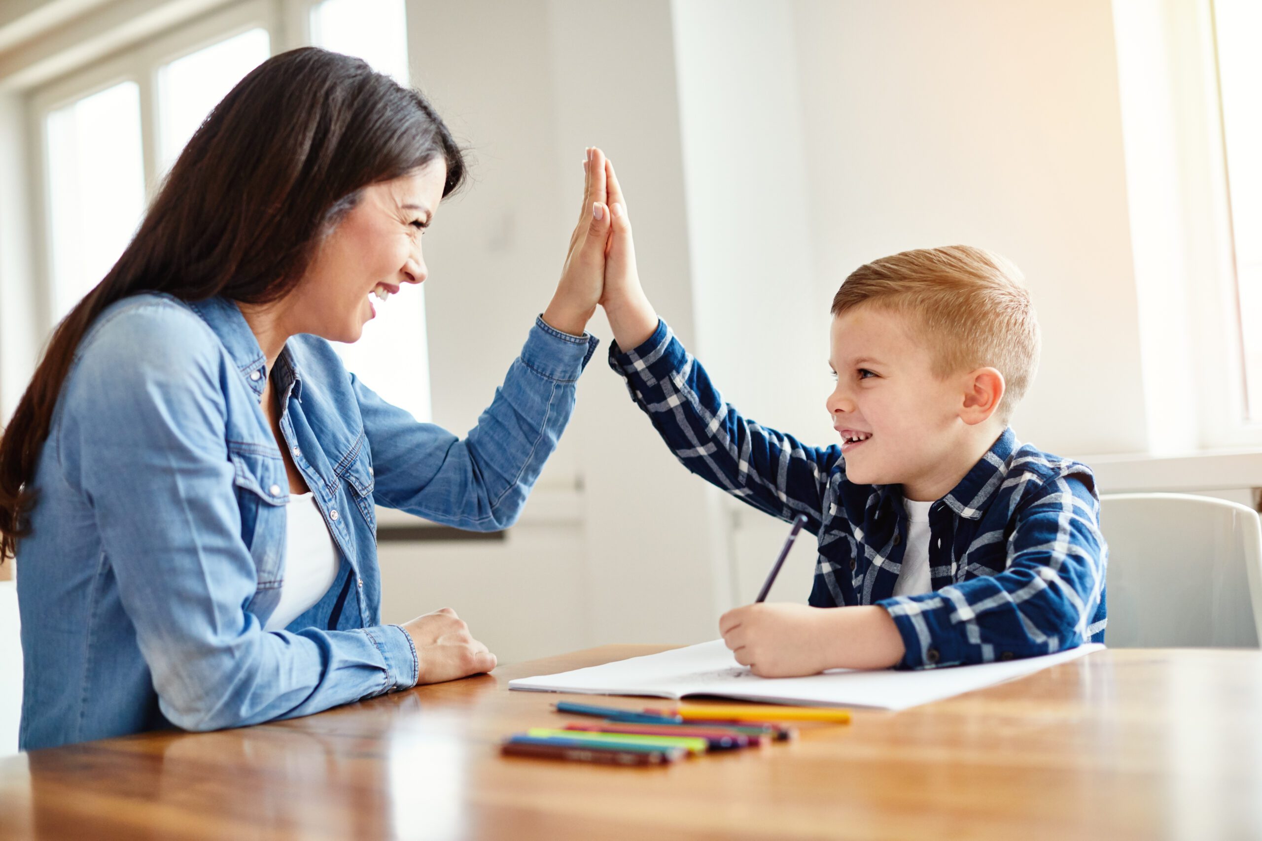 Mother and son giving a high five at a table